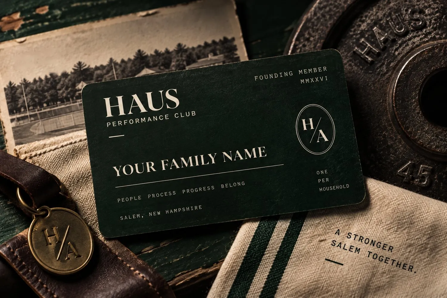 HAUS Performance Club founding member card on a table with an iron plate, leather strap, and brass H/A tag